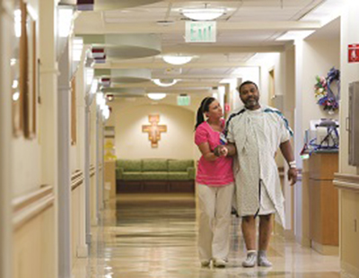 photo of a caregiver walking in the hallway with a patient