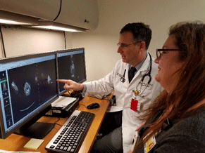 Medical professionals reviewing screenings on two computer monitors